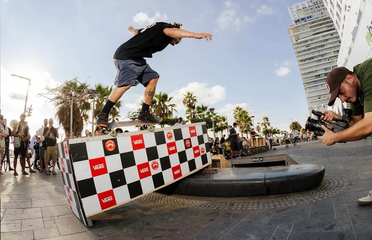 A skater clearing the checkerboard obstacle as Arthur films at the Golda contest