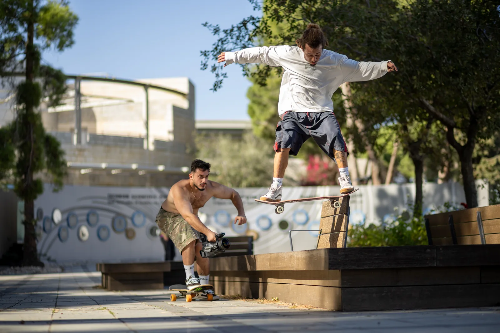 Arthur rolling alongside a skater to film a ledge trick